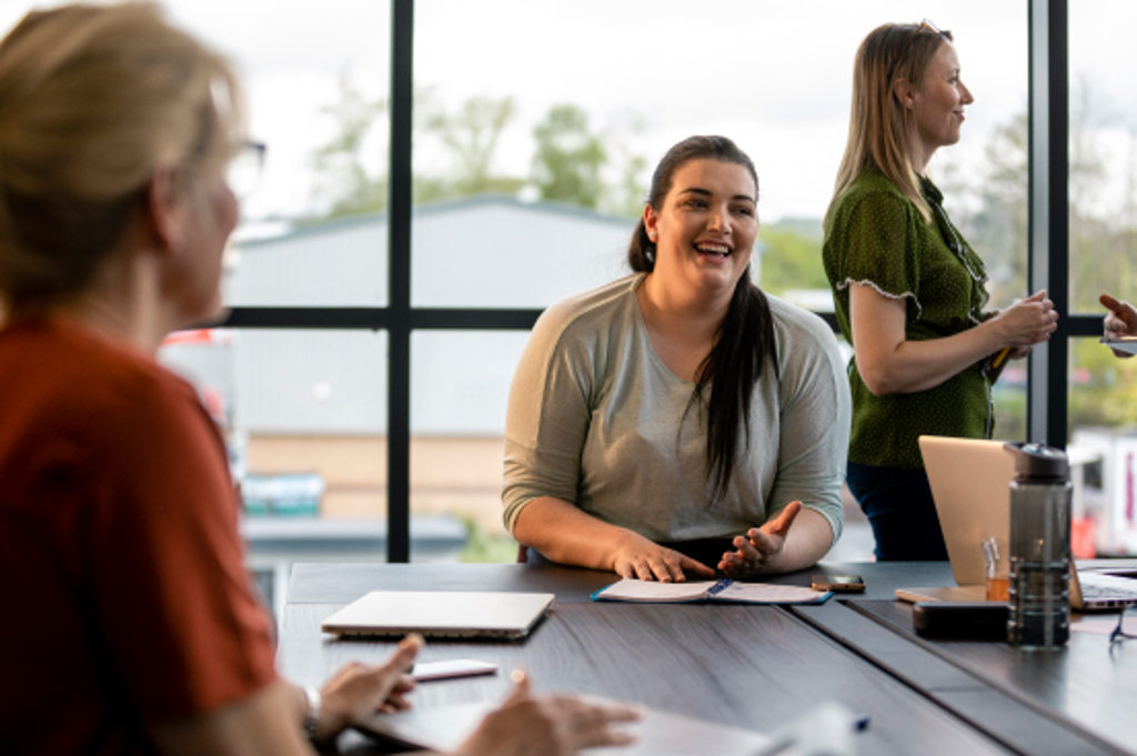 This image depicts a business owner in a conference room and talking to colleagues.