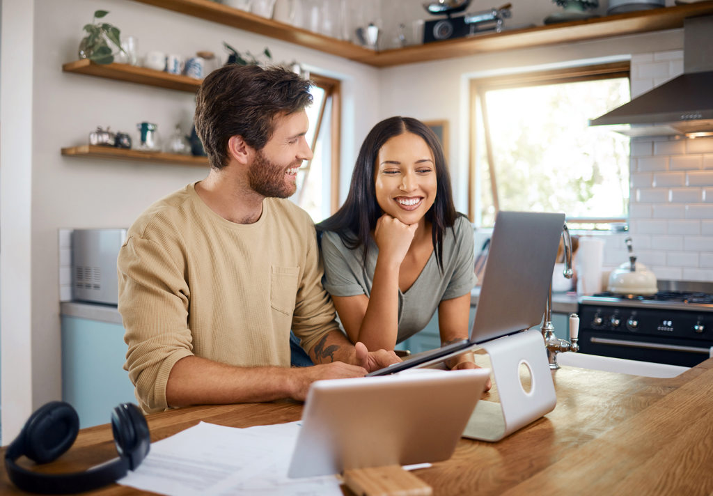 Couple at kitchen island on laptop smiling